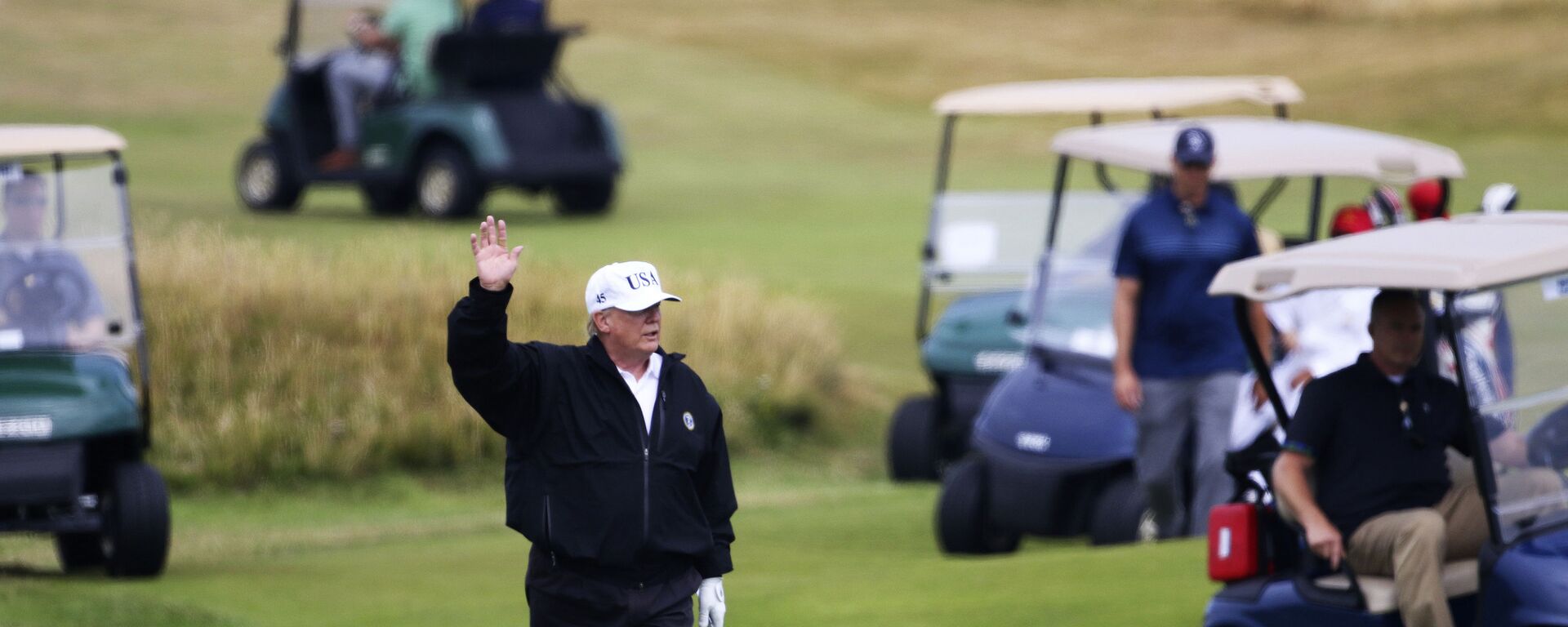 FILE - In this July 14, 2018 file photo, President Donald Trump waves to protesters while playing golf at Turnberry golf club, in Turnberry, Scotland - Sputnik International, 1920, 16.02.2023