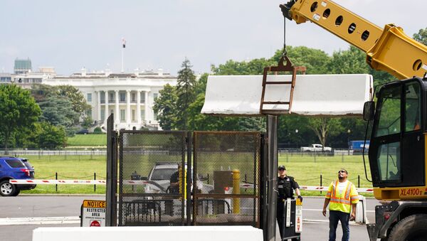 A pedestrian ducks under a concrete barrier while a crane removes barriers from around the White House as workers begin to take down fences that were installed during the recent demonstrations against racial inequality in the aftermath of the death in Minneapolis police custody of George Floyd, on the streets near the White House in Washington, U.S., June 10, 2020 - Sputnik International