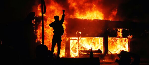 A protester gestures as buildings burn during continued demonstrations against the death in Minneapolis police custody of African-American man George Floyd, in Minneapolis, Minnesota, U.S., May 30, 2020 - Sputnik International