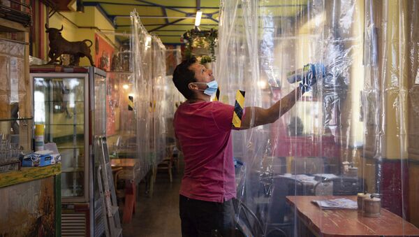 Cafe owner Francini Osorio sprays air sanitiser where he has installed an air purifier and 35 clear shower curtains - Sputnik International