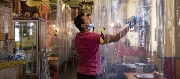 Cafe owner Francini Osorio sprays air sanitiser where he has installed an air purifier and 35 clear shower curtains Cafe owner Francini Osorio sprays air sanitiser where he has installed an air purifier and 35 clear shower curtains - Sputnik International