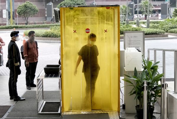 A woman reacts as she is sprayed with disinfectant inside a chamber as a precaution against the new coronavirus before entering a shopping mall in Jakarta, Indonesia, Tuesday, June 9, 2020. As Indonesia's overall virus caseload continues to rise, the capital city has moved to restore normalcy by lifting some restrictions this week, saying that the spread of the virus in the city of 11 million has slowed after peaking in mid-April.  - Sputnik International