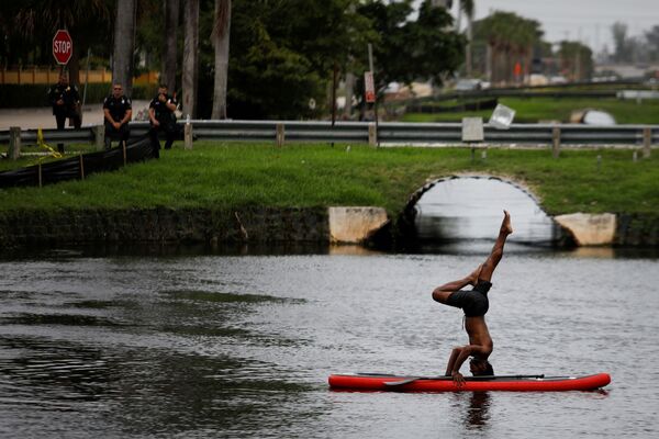 A man stands on his head on a paddle board as pollice officers look at him during a protest against racial inequality in the aftermath of the death in Minneapolis police custody of George Floyd, outside Trump National Doral golf resort in Doral, Florida, U.S., June 6, 2020.  - Sputnik International