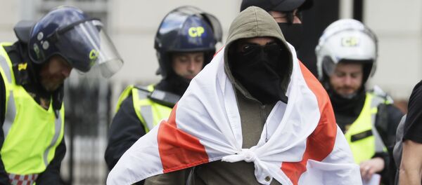 A masked protester walks as British police officers in riot gear escort him and others away in central London, as groups gather to counter-protest against a Black Lives Matter demonstration, Saturday, June 13, 2020. - Sputnik International