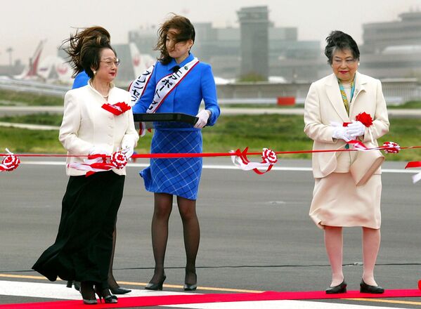 While in the strong wind, Japanese Land and Transport Minister Chikage Ohgi (L) and Chiba Governor Akiko Domoto (R) prepare to cut the ribbon for the opening ceremony of the second runway of the New Tokyo International Airport in Narita city, suburban Tokyo, 17 April 2002. The runway opened after years of delays, due to objections by landowners and farmers, to help the country cope with an expected influx of soccer fans and tourists ahead of the upcoming 2002 FIFA World Cup Korea/Japan - Sputnik International