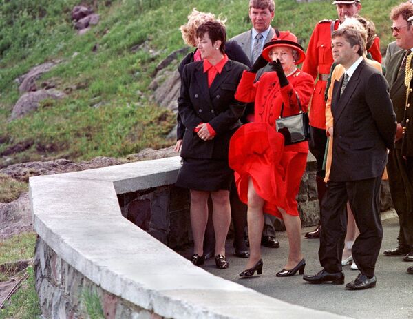 Queen Elizabeth II (C) looks out over the Atlantic Ocean as her dress blows in the wind as Canadian Heritage Minister Sheila Copps (L) and Newfoundland's Premier Brian Tobin watch at Signal Hill in St John's, Newfoundland, 25 June 1997 - Sputnik International