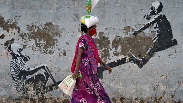 A woman wearing a protective face mask walks past a graffiti, after authorities eased lockdown restrictions that were imposed to slow the spread of the coronavirus disease (COVID-19), in Mumbai, India, June 12, 2020 - Sputnik International