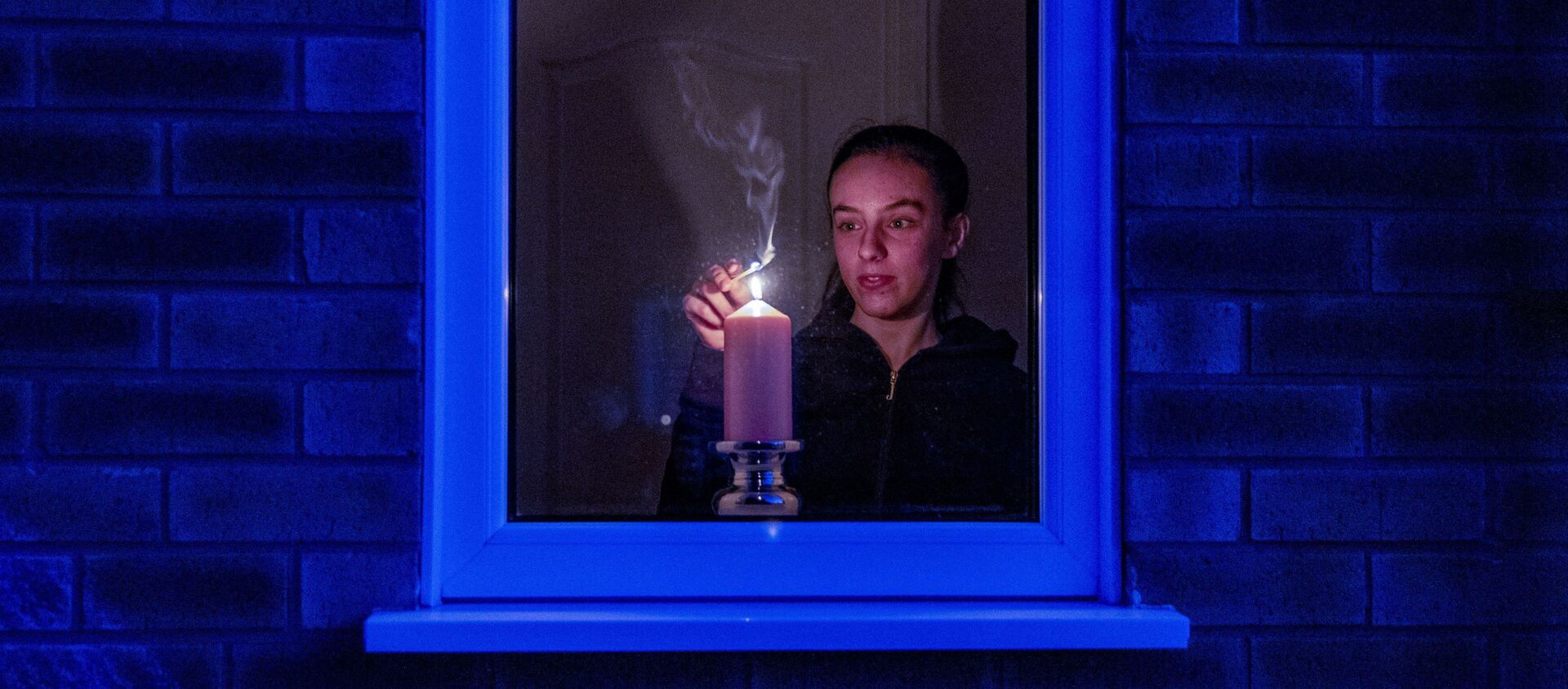 Woman lights a candle in the window of a home in Liverpool, England, after the Queen stressed the importance of maintaining the coronavirus lockdown during the Easter Bank Holiday weekend as she delivered what is believed to be her first Easter address, Saturday, April 11, 2020 - Sputnik International, 1920, 15.06.2020