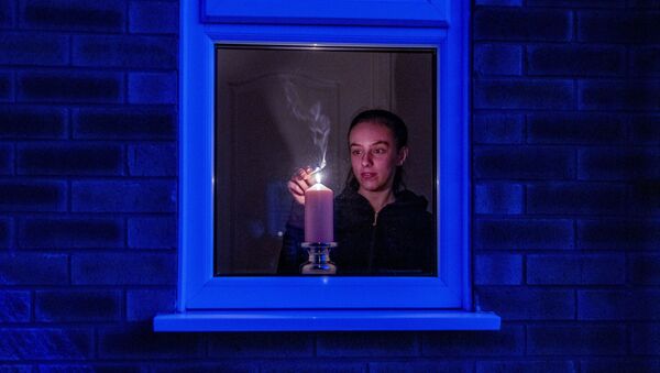 Woman lights a candle in the window of a home in Liverpool, England, after the Queen stressed the importance of maintaining the coronavirus lockdown during the Easter Bank Holiday weekend as she delivered what is believed to be her first Easter address, Saturday, April 11, 2020 - Sputnik International