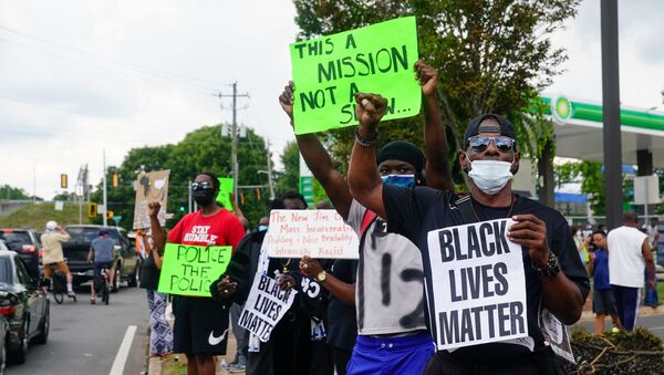 In this file photo taken on June 14, 2020 People hold signs toward traffic outside a burned Wendy’s restaurant on the second day following the police shooting death of Rayshard Brooks in the restaurant parking lot, in Atlanta, Georgia. - Sputnik International
