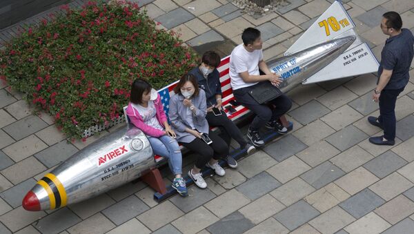 Chinese women wearing masks sit on a bench with a U.S. flag at a mall in Beijing, China, Tuesday, June 6, 2017 - Sputnik International