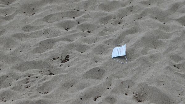 A protective face mask lies on the sand at Playa de Palma beach ahead of Spain's official reopening of the borders June 21 following the coronavirus disease (COVID-19) outbreak, in Palma de Mallorca, Spain June 16, 2020.  - Sputnik International
