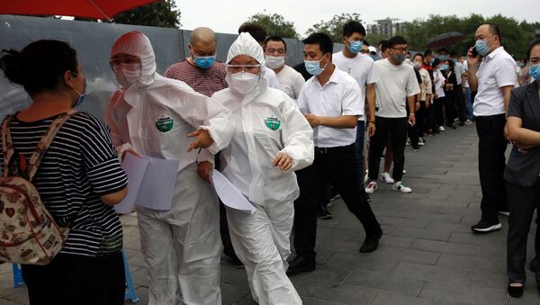 Medical workers in protective suits attend to people lining up outside a site for nucleic acid tests, following new cases of coronavirus disease (COVID-19) infections in Beijing, China June 17, 2020.  REUTERS/Tingshu Wang - Sputnik International