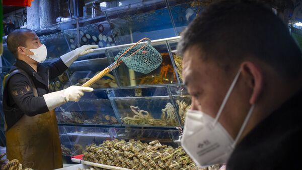 A customer wears a face mask as he shops for seafood at a market in Beijing, Saturday, March 14, 2020. The United States declared a state of emergency Friday as many European countries went on a war footing amid mounting deaths as the world mobilized to fight the widening coronavirus pandemic. For most people, the new coronavirus causes only mild or moderate symptoms, such as fever and cough. For some, especially older adults and people with existing health problems, it can cause more severe illness, including pneumonia.  - Sputnik International