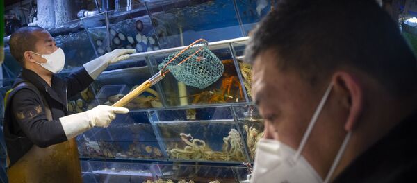 A customer wears a face mask as he shops for seafood at a market in Beijing, Saturday, March 14, 2020. The United States declared a state of emergency Friday as many European countries went on a war footing amid mounting deaths as the world mobilized to fight the widening coronavirus pandemic. For most people, the new coronavirus causes only mild or moderate symptoms, such as fever and cough. For some, especially older adults and people with existing health problems, it can cause more severe illness, including pneumonia.  - Sputnik International