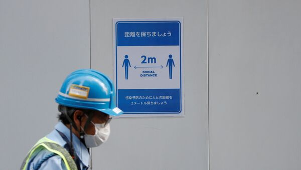 A worker passes by a social distancing sign with a face mask - Sputnik International