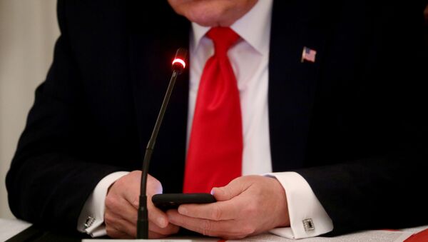 U.S. President Donald Trump is seen tapping the screen on a mobile phone during a roundtable discussion on the reopening of small businesses in the State Dining Room at the White House in Washington, U.S., June 18, 2020 - Sputnik International