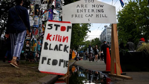 People walk by signs at a barrier set up at the edge of the self-proclaimed CHAZ/CHOP zone around the Seattle Police Department's East Precinct as people call for the defunding of police and protest against racial inequality in the aftermath of the death in Minneapolis police custody of George Floyd, in Seattle, Washington, U.S. June 14, 2020 - Sputnik International
