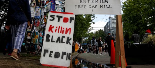 People walk by signs at a barrier set up at the edge of the self-proclaimed CHAZ/CHOP zone around the Seattle Police Department's East Precinct as people call for the defunding of police and protest against racial inequality in the aftermath of the death in Minneapolis police custody of George Floyd, in Seattle, Washington, U.S. June 14, 2020 - Sputnik International