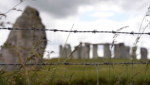The Stonehenge stone circle is seen through a barbed wire, where official Summer Solstice celebrations were cancelled due to the spread of the coronavirus disease (COVID-19), near Amesbury, Britain June 20, 2020 - Sputnik International