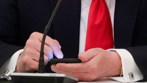 U.S. President Donald Trump is seen tapping the screen on a mobile phone at the approximate time a tweet was released from his Twitter account, during a roundtable discussion on the reopening of small businesses in the State Dining Room at the White House in Washington, U.S., June 18, 2020 - Sputnik International
