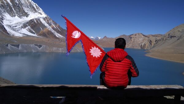   Man sitting on the shore of Tilicho Lake in Nepal, holding flag - Sputnik International