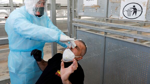 A healthcare worker swabs the nose of a Palestinian worker for the coronavirus disease (COVID-19) testing upon his return from Israel, outside the Israeli-controlled Meitar checkpoint, near Hebron in the Israeli-occupied West Bank April 7, 2020. - Sputnik International