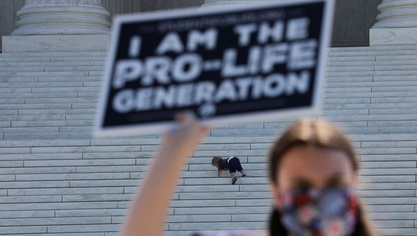 A child plays on the steps of the U.S. Supreme Court building as an anti-abortion activist holds a sign during a demonstration outside the court in Washington, U.S., June 29, 2020 - Sputnik International