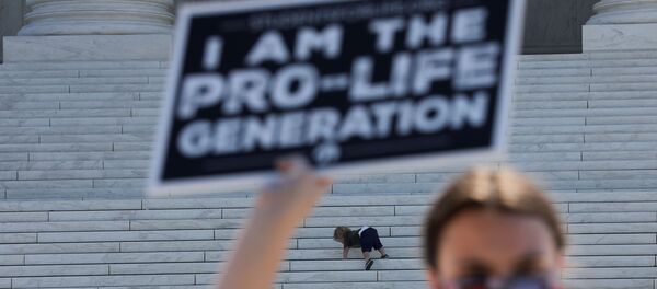 A child plays on the steps of the U.S. Supreme Court building as an anti-abortion activist holds a sign during a demonstration outside the court in Washington, U.S., June 29, 2020 A child plays on the steps of the U.S. Supreme Court building as an anti-abortion activist holds a sign during a demonstration outside the court in Washington, U.S., June 29, 2020 - Sputnik International