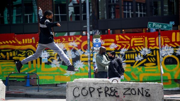 Jamil jumps onto a barricade with graffiti reading Cop free zone as his parents stand nearby at the CHOP area as people continue to occupy space and protest against racial inequality in the aftermath of the death in Minneapolis police custody of George Floyd, in Seattle, Washington, U.S. June 28, 2020.  - Sputnik International