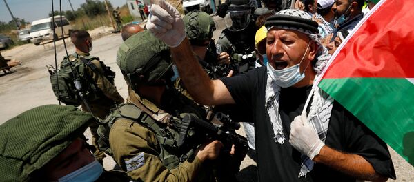 FILE PHOTO: A demonstrator holding a Palestinian flag gestures in front of Israeli forces during a protest against Israel's plan to annex parts of the occupied West Bank, in Haris June 26, 2020. FILE PHOTO: A demonstrator holding a Palestinian flag gestures in front of Israeli forces during a protest against Israel's plan to annex parts of the occupied West Bank, in Haris June 26, 2020. - Sputnik International