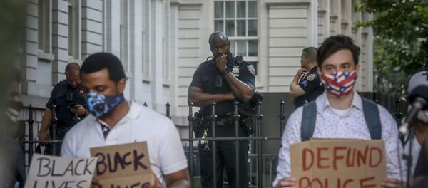 A New York City police officer, among a detail of police guarding City Hall, watches as organizers with City Workers4Justice–an activist organization for city employees–prepare to lead a rally and march calling on Mayor Bill de Blasio to defund the police department, Thursday June 25, 2020, in New York. A New York City police officer, among a detail of police guarding City Hall, watches as organizers with City Workers4Justice–an activist organization for city employees–prepare to lead a rally and march calling on Mayor Bill de Blasio to defund the police department, Thursday June 25, 2020, in New York. - Sputnik International