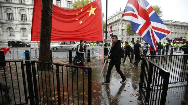 A supporter of Chinese President Xi Jinping carries a large British flag past the national flag of China outside Downing Street  where he is meeting the British Prime Minister David Cameron in London, Wednesday, Oct.  21, 2015 - Sputnik International