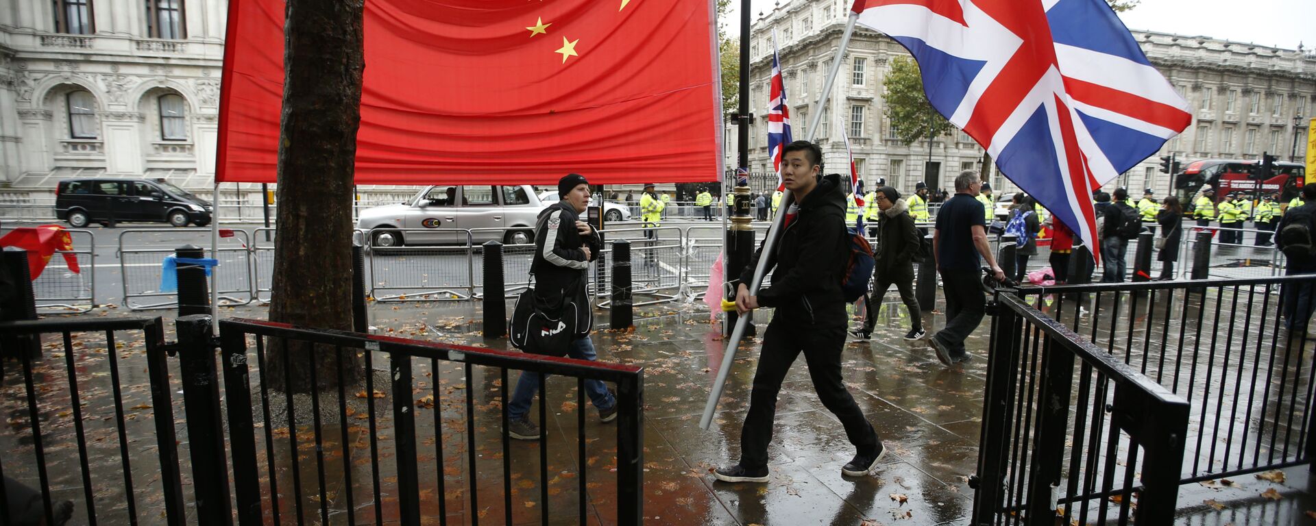 A supporter of Chinese President Xi Jinping carries a large British flag past the national flag of China outside Downing Street  where he is meeting the British Prime Minister David Cameron in London, Wednesday, Oct.  21, 2015 - Sputnik International, 1920, 23.02.2024