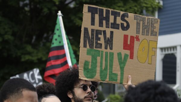 A Black Lives Matter activist holds a banner warning of a new 4th of July - Sputnik International