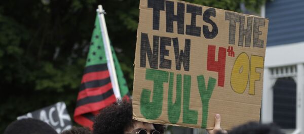 A Black Lives Matter activist holds a banner warning of a new 4th of July - Sputnik International