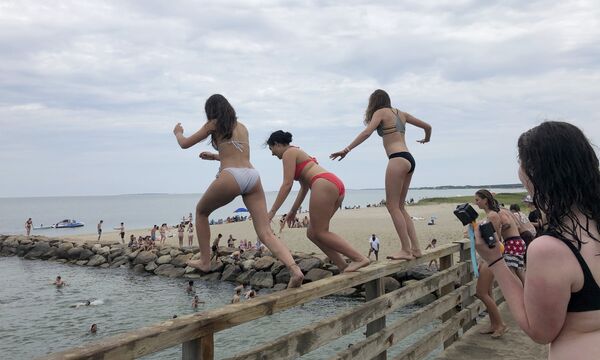 Women jump from a bridge into Sengekontacket Pond in Edgartown, Massachusetts on the island of Martha's Vineyard, June 27, 2020 - Sputnik International