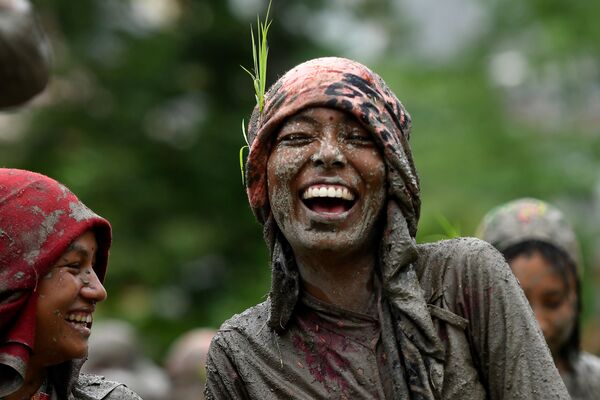 A woman smiles in a rice paddy field during National Paddy Day, which marks the start of the annual rice planting season, in Tokha village on the outskirts of Kathmandu on June 29, 2020 - Sputnik International