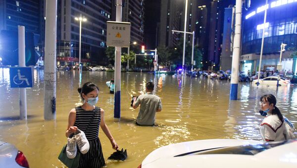 People wade through floodwater at an intersection after heavy rainfall led to flooding in Hefei, Anhui province, China, 27 June 2020 - Sputnik International