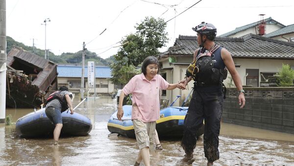 A rescue worker helps local residents at a flooded area caused by heavy rain along Kuma River in Hitoyoshi, Kumamoto prefecture, southern Japan, in this photo taken by Kyodo 4 July 2020 - Sputnik International