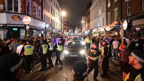 Police officers move revellers from the road to allow traffic to pass in the Soho area of London on July 4, 2020, after the police re-opened the road at 2300 following a further easing of restrictions to allow pubs and restaurants to open during the novel coronavirus COVID-19 pandemic. - Sputnik International