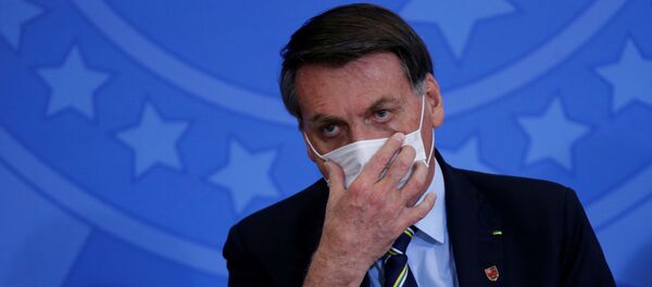 Brazil's President Jair Bolsonaro adjusts his protective face mask during the inauguration ceremony of the new Communications Minister Fabio Faria (not pictured) at the Planalto Palace, in Brasilia, Brazil June 17, 2020 - Sputnik International