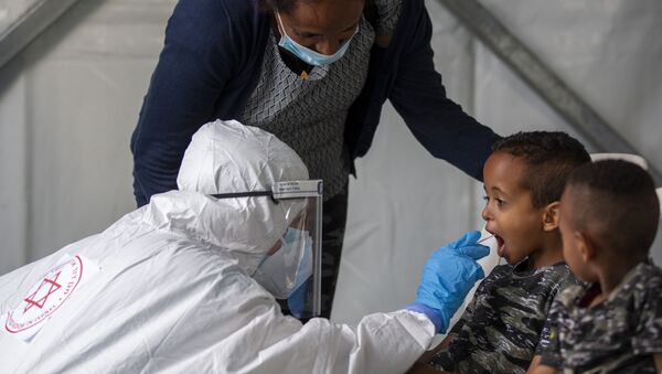 A child is tested by a healthcare worker for the coronavirus at testing center for migrants in Tel Aviv, Israel, Monday, July 6, 2020. - Sputnik International