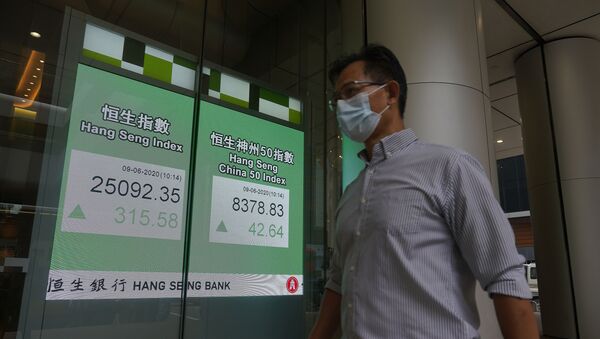 A man wearing a face mask walks past a bank electronic board showing the Hong Kong share index at Hong Kong Stock Exchange Tuesday, June 9, 2020. - Sputnik International