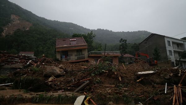 An excavator is seen next to collapsed houses at the site of a landslide following heavy rainfall, in Huangmei county of Hubei province, China July 8, 2020 - Sputnik International
