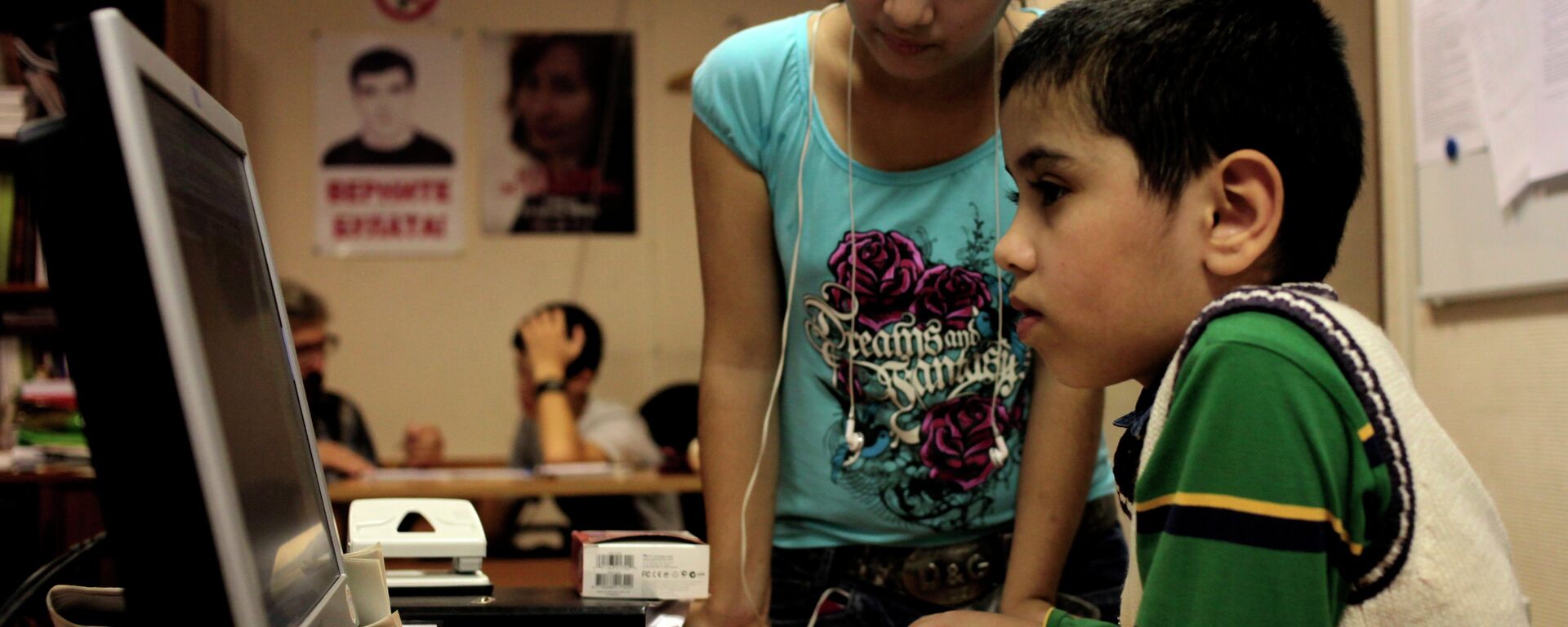 At a refugee school in Moscow, two children play on a computer, while other students are tutored by volunteer teachers. - Sputnik International, 1920, 04.08.2022