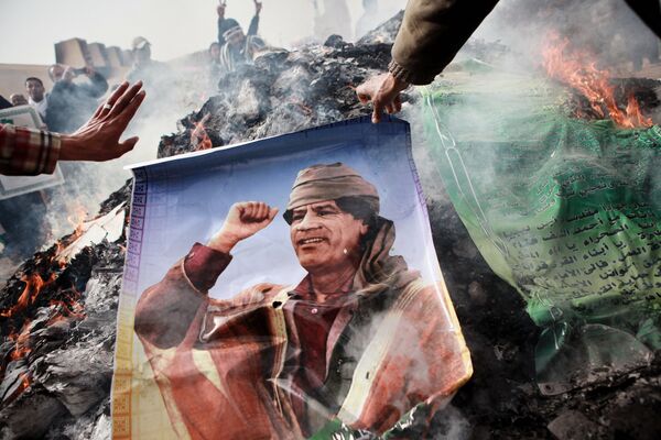 Rebel burns a poster depicting Libyan leader Muammar Gaddafi - Sputnik International