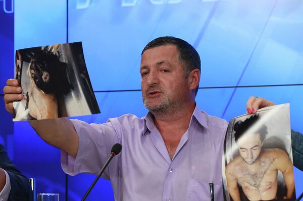 Abdulbaki Todashev showing photos of what he said was his son’s bullet-riddled body, at a press conference in Moscow on May 30 - Sputnik International