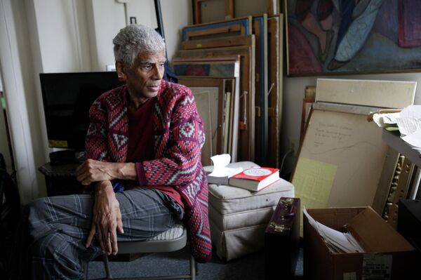 Patterson sitting in his Washington apartment with his mother’s paintings stacked against the wall. - Sputnik International