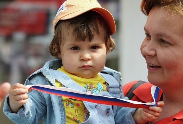 A woman with a child, who holds a ribbon having the colors of the Russian flag - Sputnik International